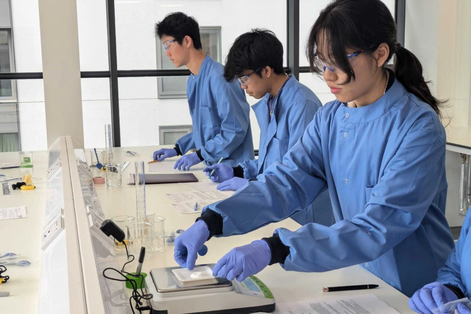 Verto students in lab coats and gloves conducting a science experiment