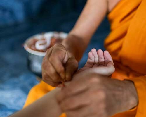 Monk tying bracelet on student traveling abroad with Verto Education