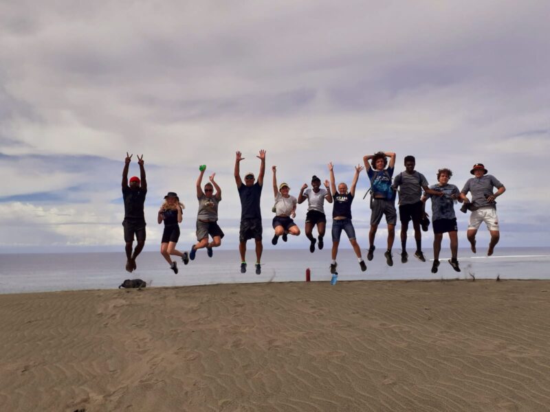 Students jumping on a beach in Fiji
