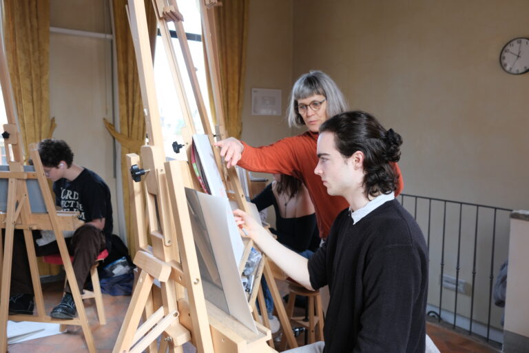 A professor helping a student in "Beginning Drawing" in the Verto Florence drawing room.