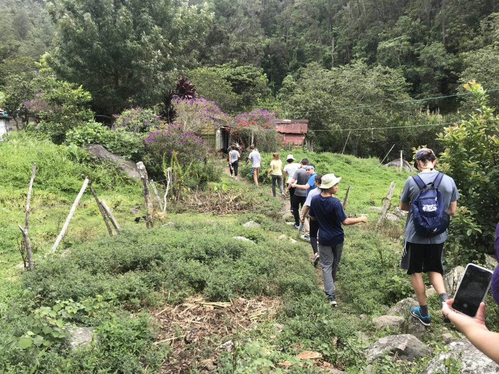 Verto Education students hiking through a lush rural landscape toward a local village abroad