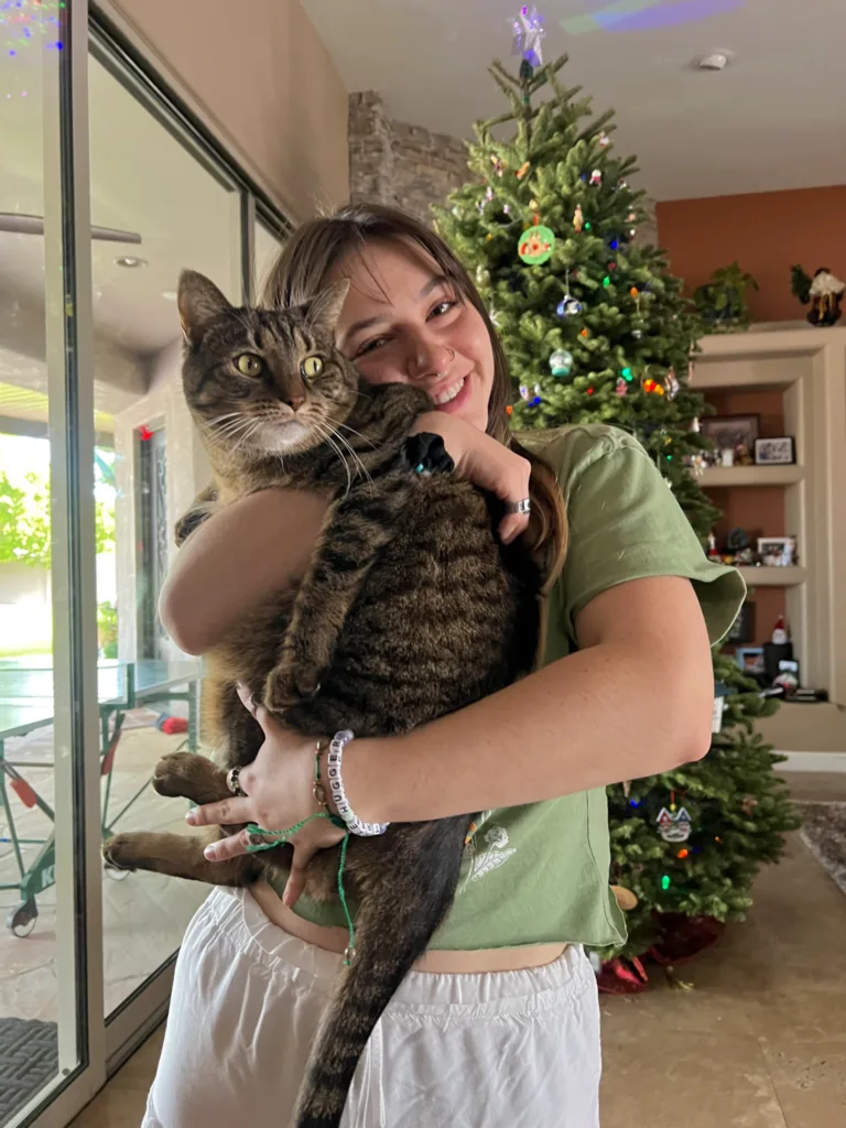 Student smiling holding a large short hair house cat