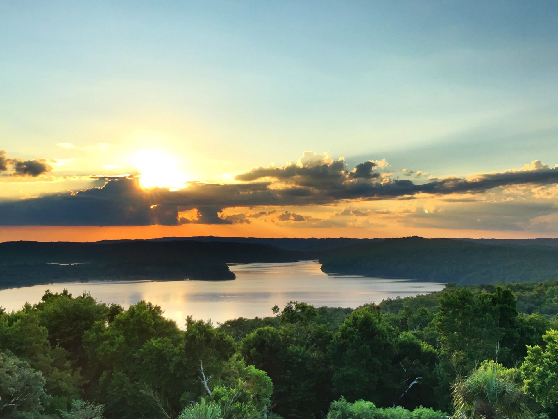 Photographic image depicts a sunset over a river.