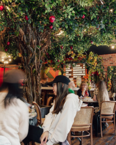 People dine around a tree at Apple Butter cafe- a great spot to work in while studying abroad in London!