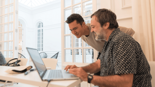 Professor in Spain assisting a student on the computer.