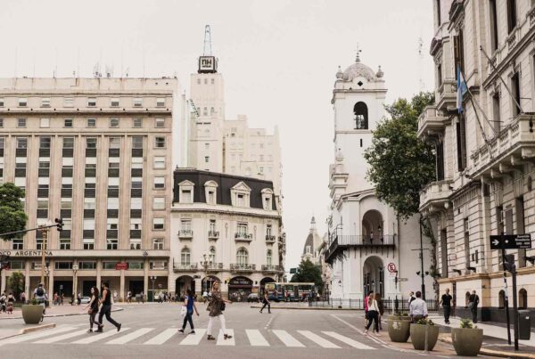 Photo: People crossing street in Buenos Aires in front of beautiful white and beige architecture, one of the many sites you'll see when you study abroad in buenos aires.
