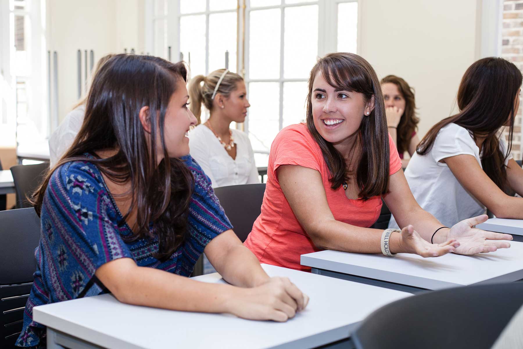 Photo: Two students talking, smiling and laughing in class