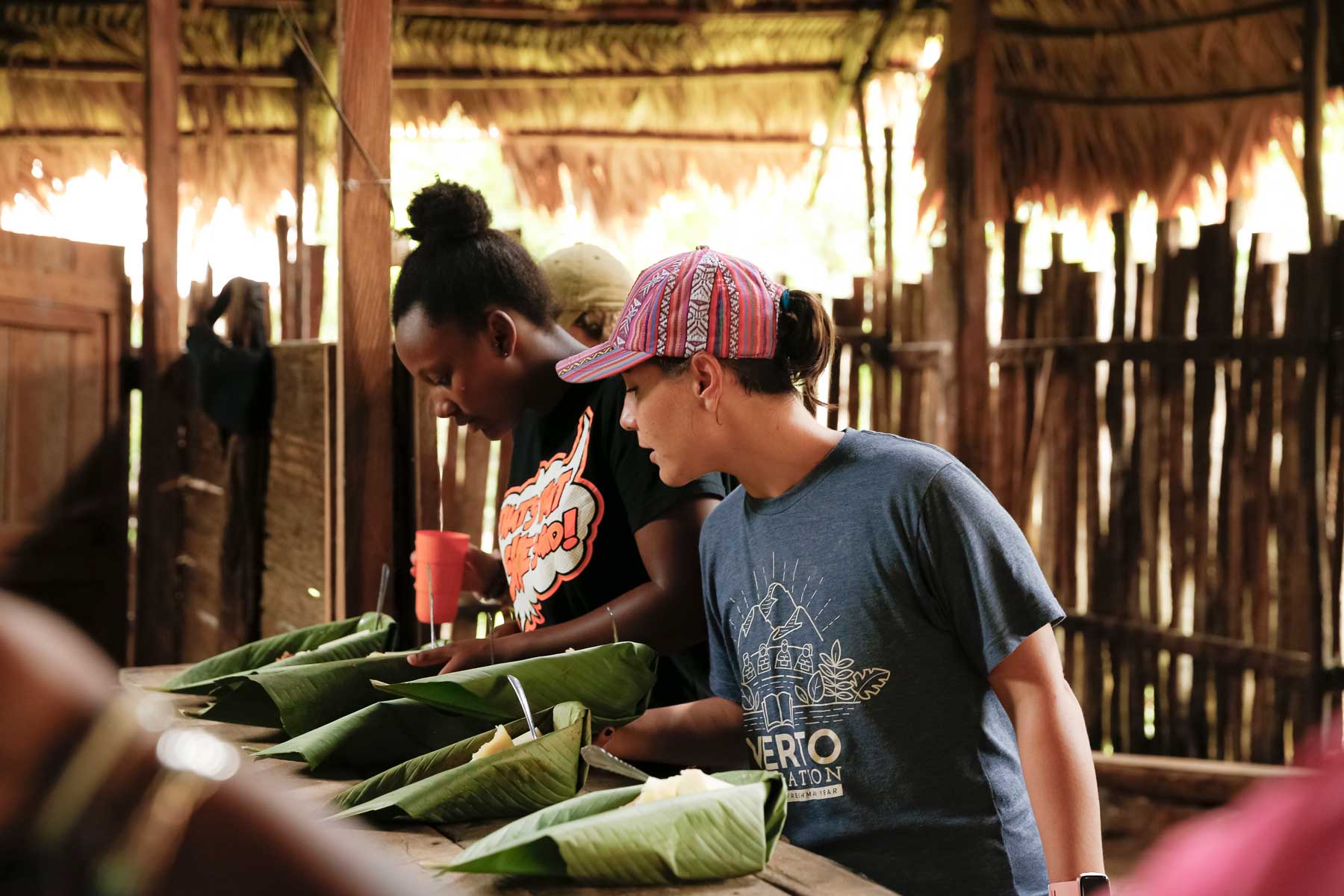 Photo: Verto Education students surveying meals served in tropical jungle leaves and grass roof hut